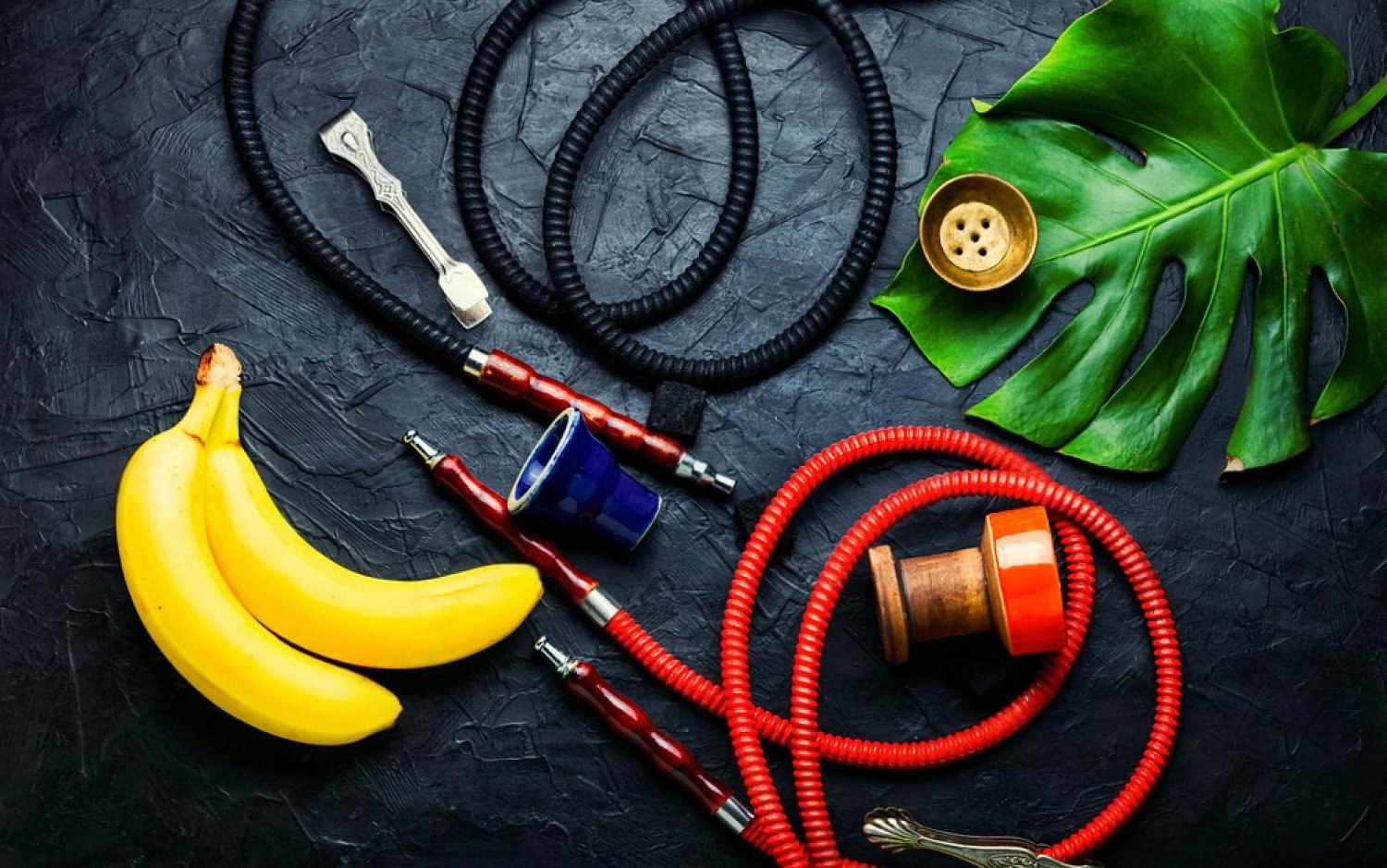 Hookah pipes with fruit flavours and accessories arranged on a dark background